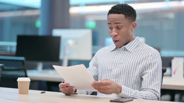 African Businessman Reacting to Loss While Reading Documents