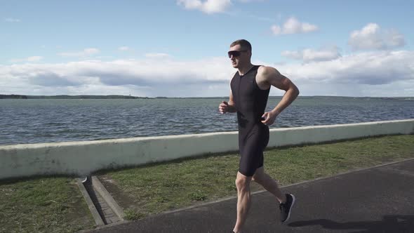 Professional Runner Runs on a Road Near the Lake Athlete Trains in on a Sunny Day Running Before