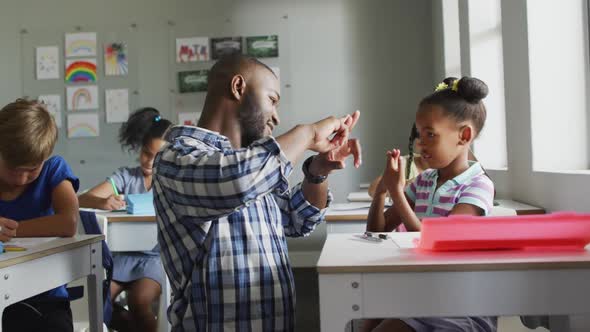 Video of happy african american teacher learning african american girl how to count in classroom