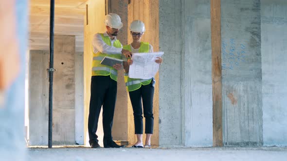 Female and Male Architects Engineers Are Having a Conversation at a Construction Site