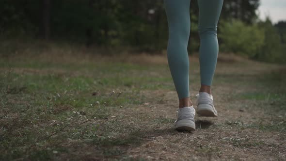 Side View of a Woman Running Uphill in a Forest