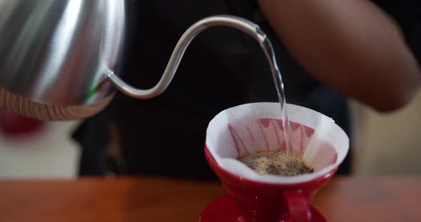 Young male barista in trendy modern cafe coffee shop pours boiling water over coffee grounds making