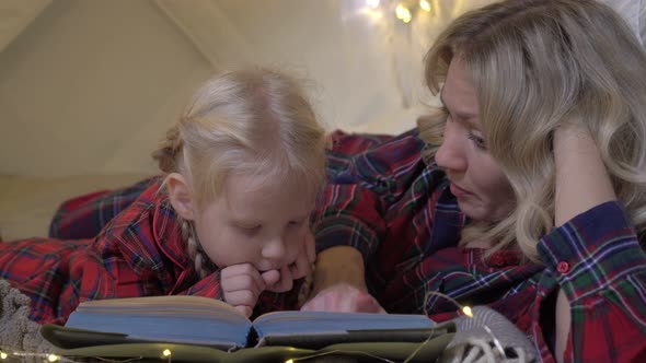 Parents with a Child Read a Fairy Tale Before Bedtime