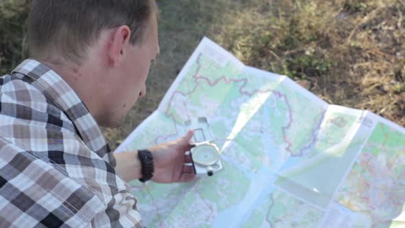 A man with a map and a compass in his hands is looking for a way