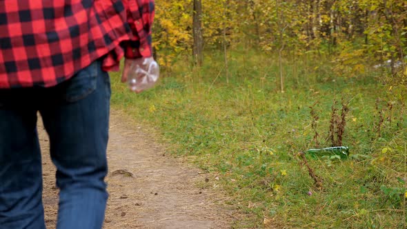 Unrecognizable Man Throws a Plastic Bottle Into the Grass in the Forest Slow Motion