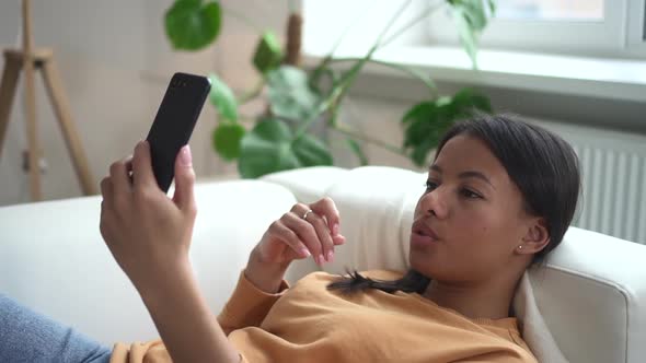 On Phone African Woman is Talking Through Web Camera Phone While Lying on Couch Spbd