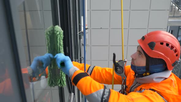 Equipped Industrial Climber Washes Windows with a Fur Coat at High Building, Slow Motion
