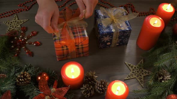 Female Hands Put and Finalize Christmas Gift on a Wooden Table