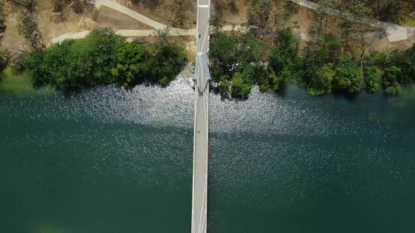 Vertical drone footage looking down on small walking bridge