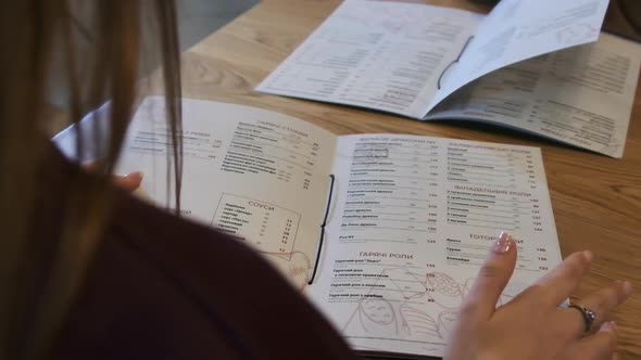 Back View of a Woman Reading a Menu in a Restaurant. Lifestyle.