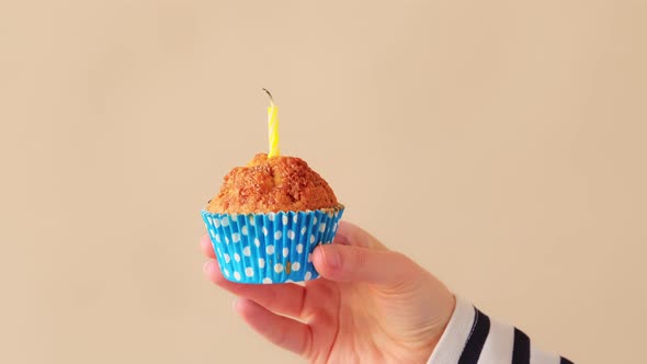 Make a wish and blow out the candle on birthday cupcake.