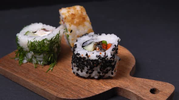 Delicious Japanese Sushi Rolls with Sesame Seeds on a Stone Board on a Black