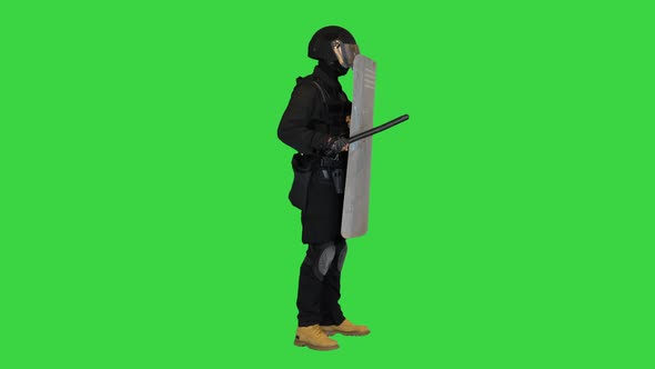 Policeman in Full Equipment for Antiriot Standing with a Shield and Rubber Baton on a Green Screen