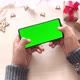 Man holding smartphone with horizontal green screen and touch on Christmas background with gifts. - VideoHive Item for Sale