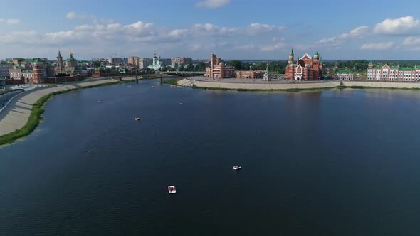 The city promenade in the heat. Townspeople goes a boats on the cool water