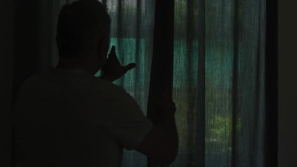 Rear view of senior caucasian man at home standing at a window