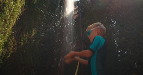 Happy Child Boy Playing with Water in Shower of Swimming Pool Outdoors