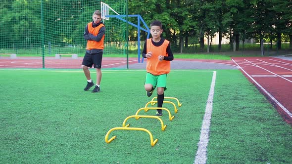 Football Coach Watching How His Pupils Doing Running Exercises with Overcoming Obstacles