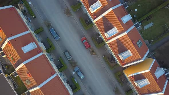 Aerial view of suburban area with residential houses and parked cars.