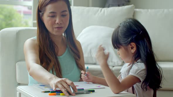 Cheerful young mother and daughter drawing on paper