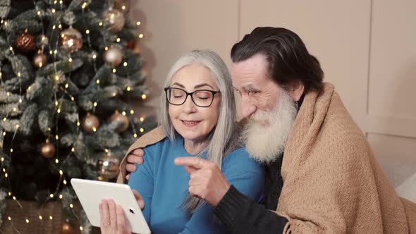 Senior Pensioner Couple with Digital Tablet Have Video Call on Christmas