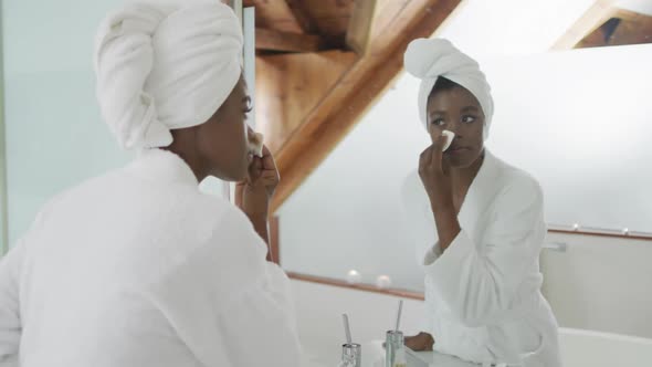 African american attractive woman removing make up in bathroom