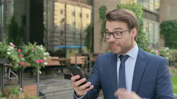 Businessman Celebrating on Smartphone while Walking in Street in Slow Motion