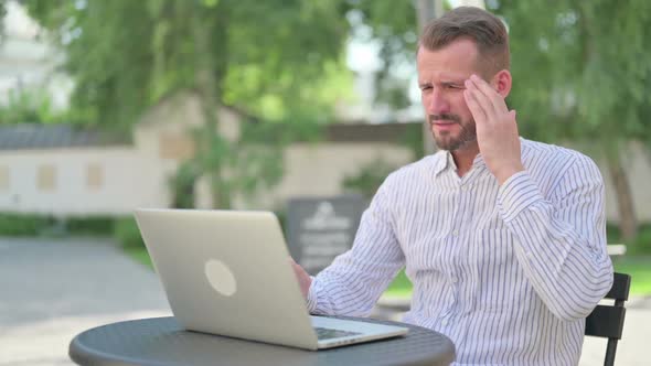 Middle Aged Man with Laptop Having Headache