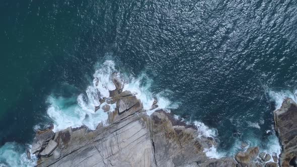 Top down drone shot of waves crashing into beautiful rocks on the coastline of the Cape Peninsula, S