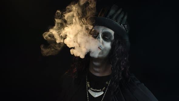 Sinister Man with Professional Skull Makeup Exhaling Cigarette Smoke From His Mouth and Nose