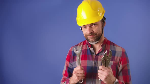 Young Handsome Man with a Beard Wearing Safety Helmet and Showing His Tools with a Big Toothy Smile
