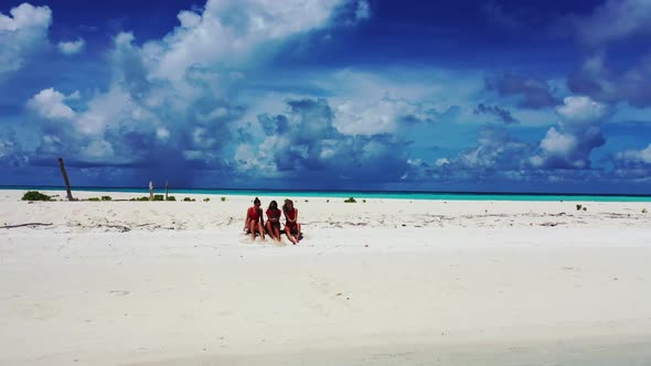 Girls enjoying life on exotic coast beach trip by blue lagoon with white sand background of the Mald