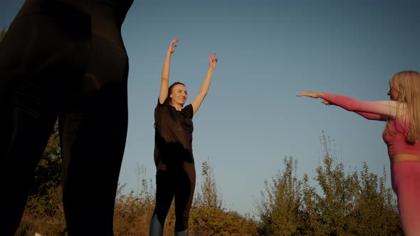 Against the Background of the Bright Orange Sunset Sky Group Woman's Practicing 