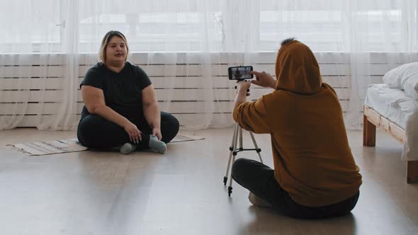 Cute Confident Overweight Woman Feminist and Her Friend Sitting on the Floor and Recording a Video