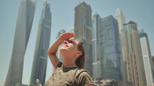 A Happy Girl is in Dubai on a Background of Skyscrapers Dubai Marina