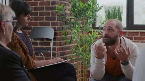 Close Up of Man Trembling and Shaking at Aa Group Therapy Session with People in Circle