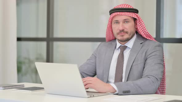 Middle Aged Arab Businessman Shaking Head as No Sign while using Laptop in Office