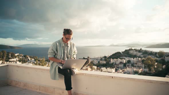 Young Woman Freelancer Working with Her Laptop on the Roof Terrace.