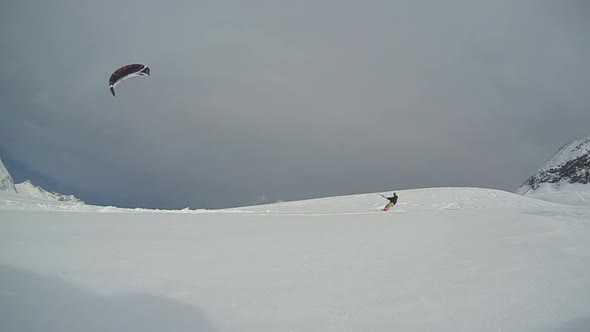 A young man snowkiting in the mountains.