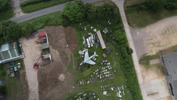 Top down descending view towards Hawker hunter military aircraft surrounded by parts on farmland in