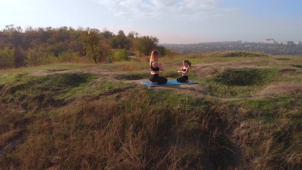 Aerial Top Drone View of Slender Young Mother Do Yoga Exercises with Child Daughter on High Hill in