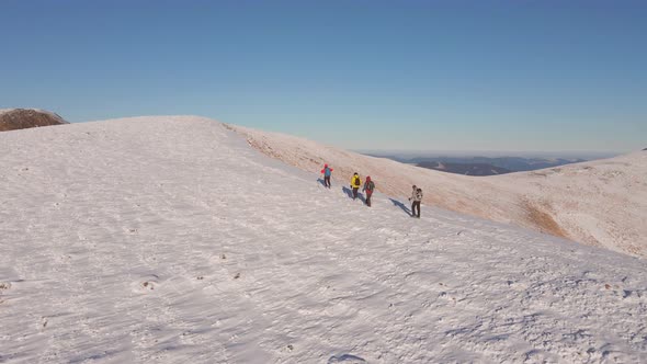 Four Climbers Walk on the Ridge of a Snowy Mountain