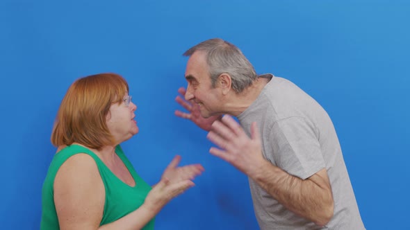 Couple Quarreling on Blue Background. Aged Couple Quarreling. Conflict, Negative Emotions.