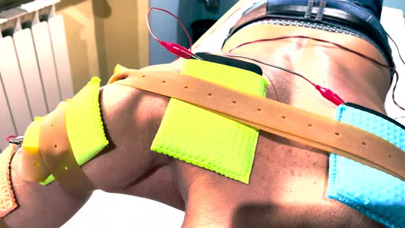 Muscle Stimulator Device with Electrodes Applied to Biceps and Shoulders By a Professional