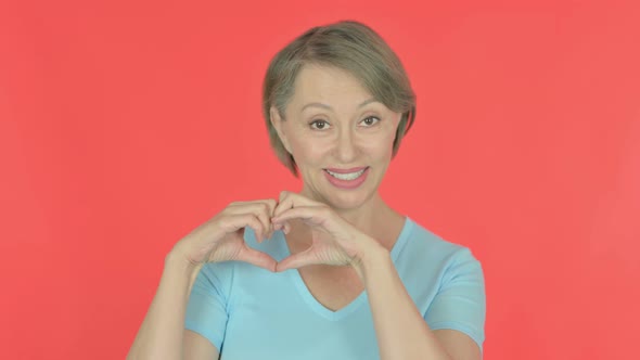 Old Woman Showing Heart Shape By Hands on Red Background