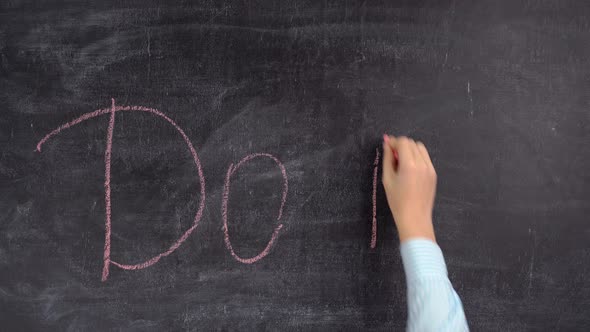 The hand of a business coach writes the phrase DO IT on a chalkboard