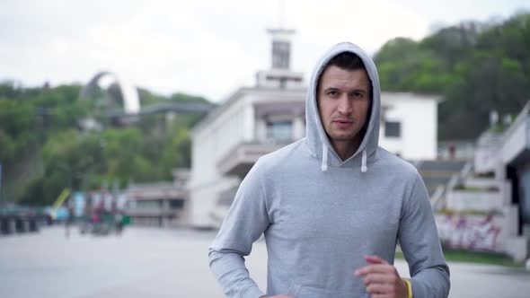 Young man in sports hoody starting run exercise in slow motion. Fit man running outdoor