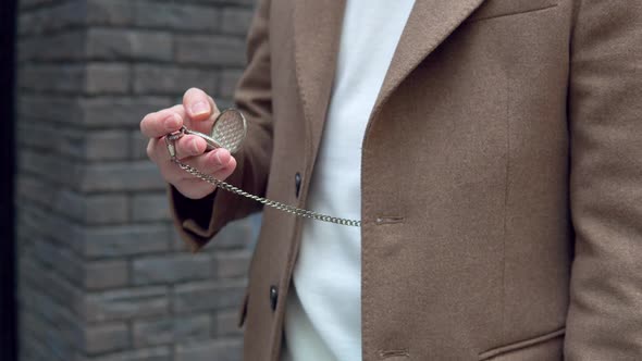 Stylish Young Man in Brown Coat with Pocket Watch on the Street