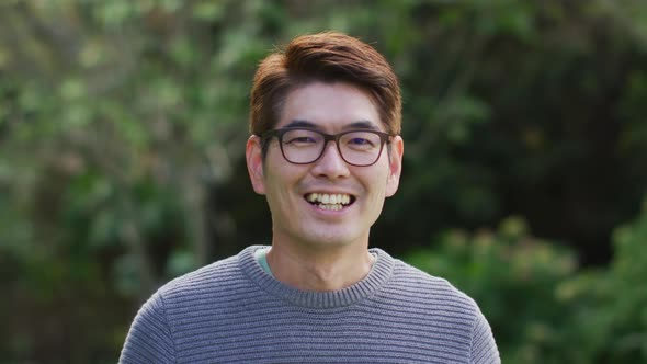 Portrait of happy asian man looking to camera smiling and laughing in garden