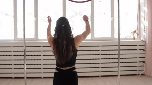 A Young Gymnastic Woman Walks to the Ring Under the Ceiling  Holds on It and Spinning Around